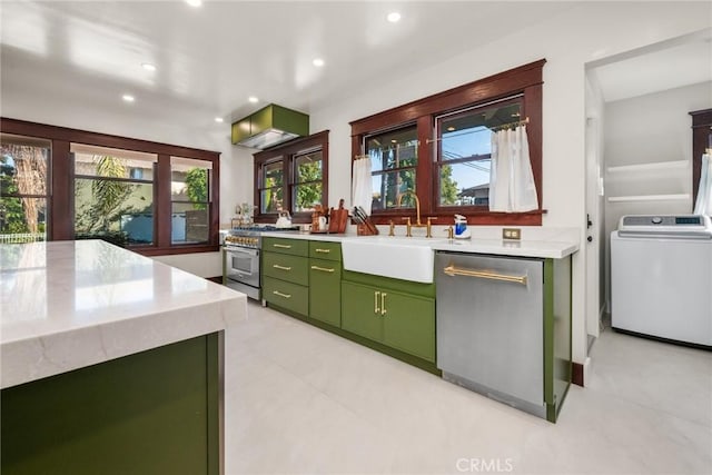 kitchen featuring stainless steel appliances, a sink, light countertops, washer / dryer, and green cabinetry