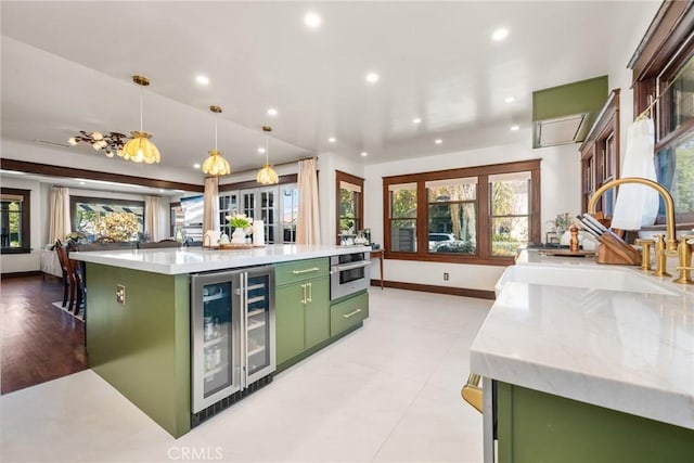 kitchen with plenty of natural light, green cabinetry, wine cooler, stainless steel oven, and a sink