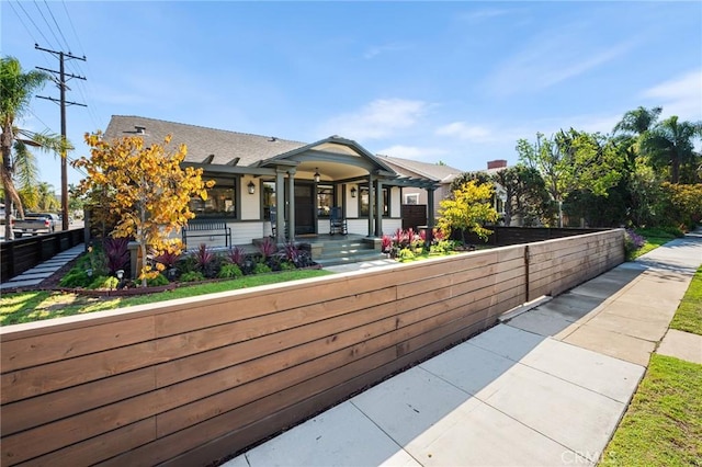 view of front of home with a fenced front yard and a porch