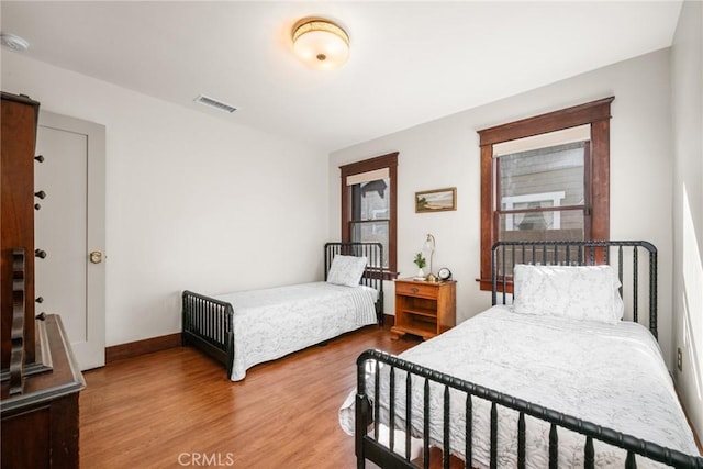 bedroom featuring visible vents, baseboards, and wood finished floors