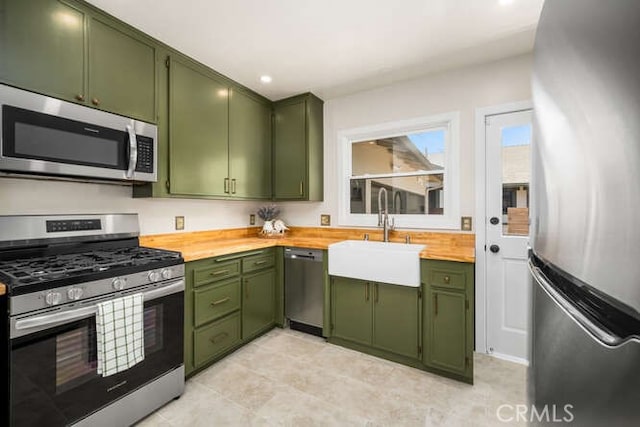 kitchen featuring appliances with stainless steel finishes, a sink, wood counters, and green cabinets