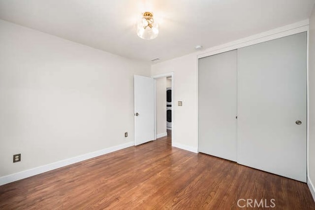 unfurnished bedroom featuring a closet, baseboards, and wood finished floors