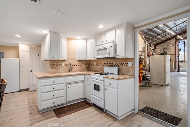 kitchen with white appliances, a sink, white cabinets, light countertops, and decorative backsplash