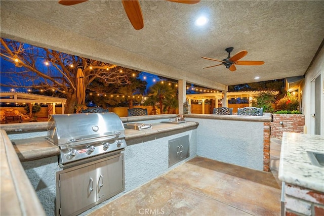 view of patio featuring a ceiling fan, a grill, and exterior kitchen