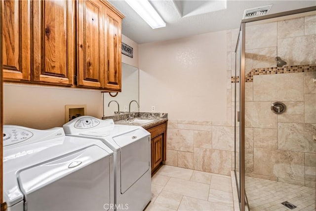 laundry area with cabinet space, visible vents, separate washer and dryer, a sink, and light tile patterned flooring