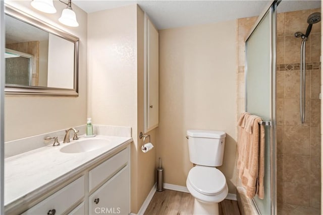 full bath with toilet, a stall shower, wood finished floors, and vanity