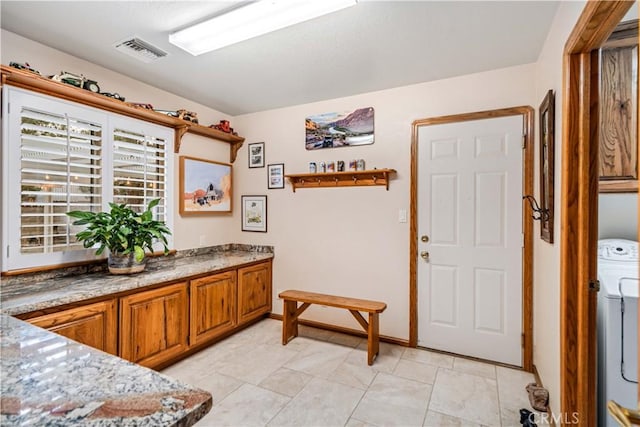 foyer with washer / clothes dryer, visible vents, and baseboards