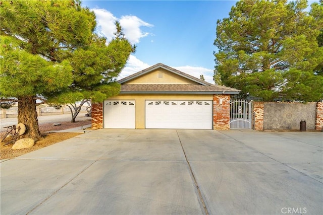 single story home featuring driveway, brick siding, a gate, and stucco siding