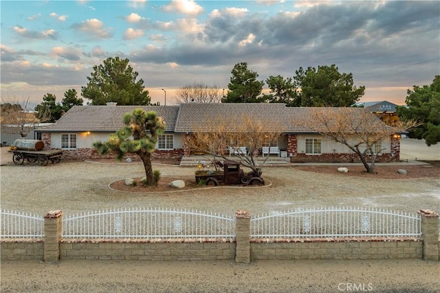 ranch-style home with a tiled roof and fence