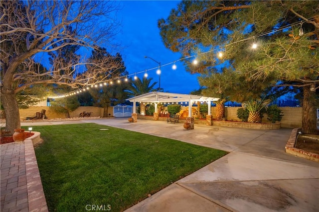 yard at twilight featuring a fenced backyard, an outdoor structure, and a patio