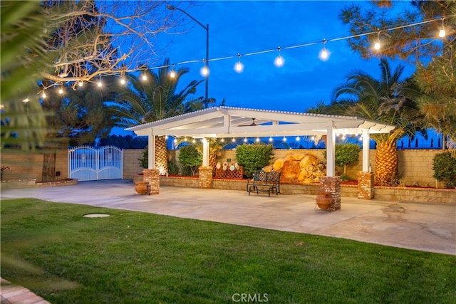 patio at twilight featuring a lawn, fence, a gate, and a pergola