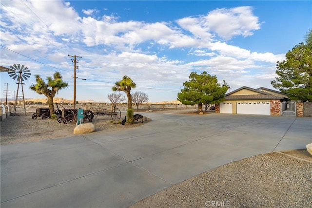 view of yard featuring concrete driveway, an attached garage, fence, and a gate