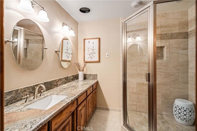 bathroom featuring a shower stall, baseboards, tile patterned flooring, and vanity