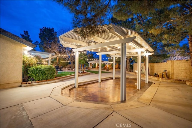 patio at twilight with fence and a pergola