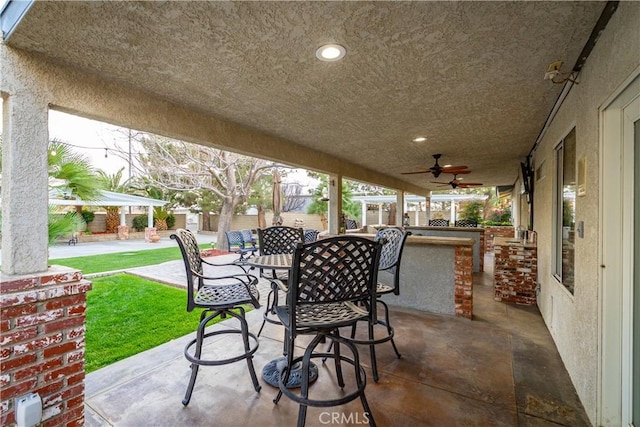 view of patio featuring a ceiling fan, outdoor dining space, and outdoor dry bar