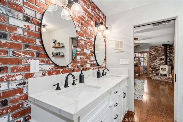 bathroom featuring a sink, brick wall, and wood finished floors