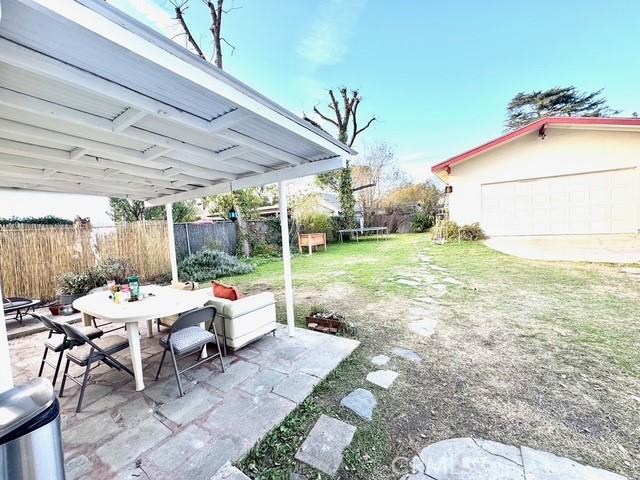 view of patio featuring a trampoline, fence, and outdoor dining space