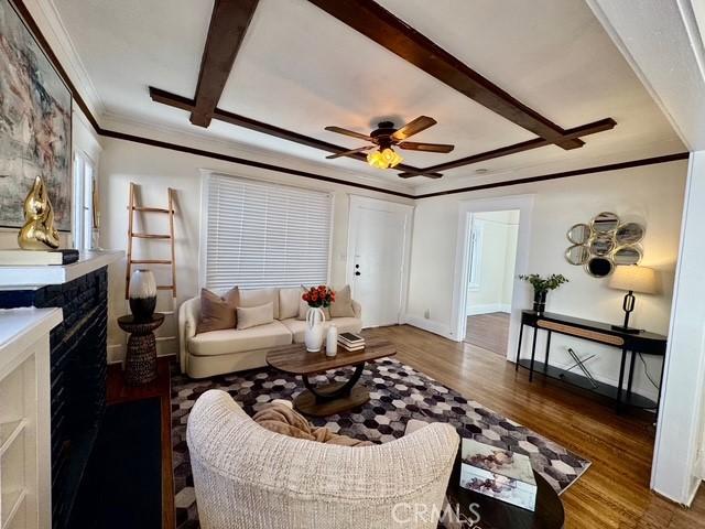 living room featuring ceiling fan, wood finished floors, a high end fireplace, baseboards, and crown molding