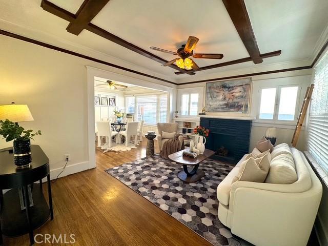 living room with a wealth of natural light, ornamental molding, and wood finished floors