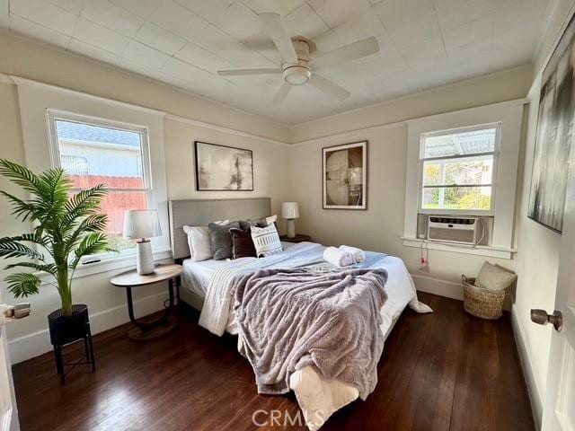 bedroom with dark wood finished floors, a ceiling fan, and baseboards