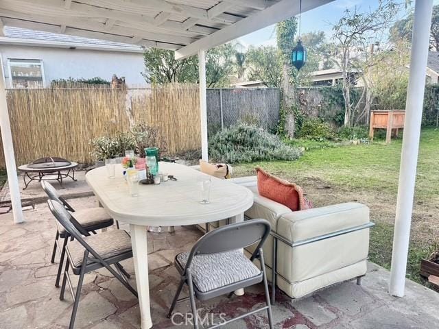 view of patio / terrace with a fire pit, outdoor dining space, and fence