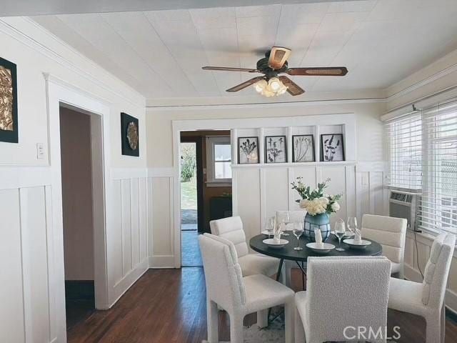 dining space featuring dark wood-type flooring, wainscoting, crown molding, and a decorative wall