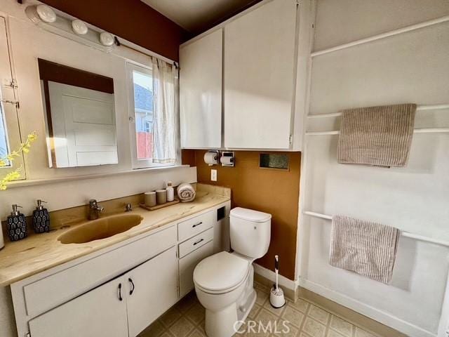 bathroom featuring vanity, toilet, and baseboards