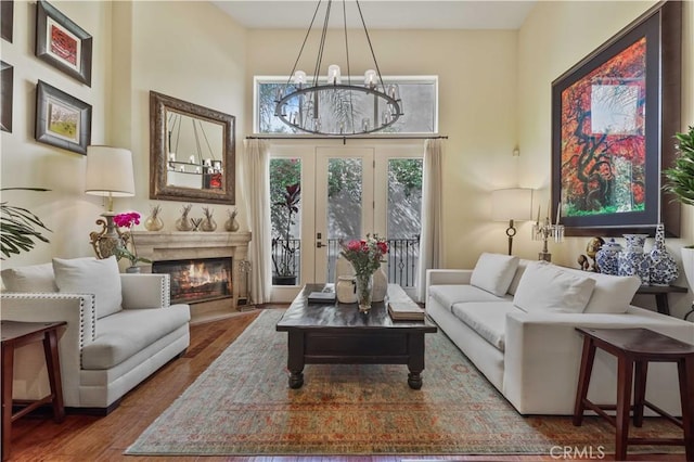 interior space featuring a chandelier, a towering ceiling, a premium fireplace, and wood finished floors