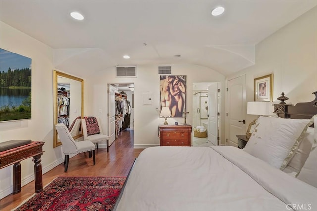 bedroom with visible vents, a walk in closet, wood finished floors, and recessed lighting