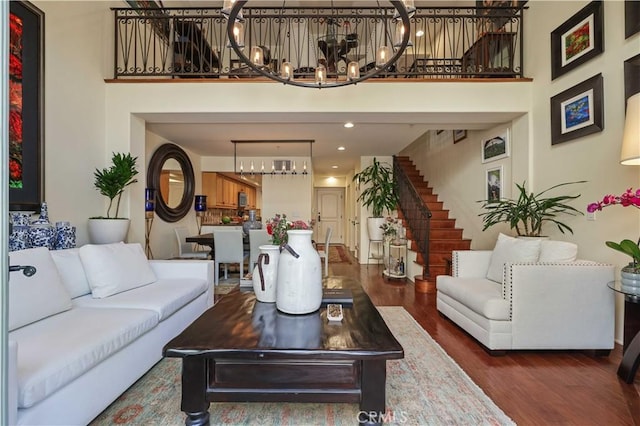 living room with a towering ceiling, stairway, and wood finished floors