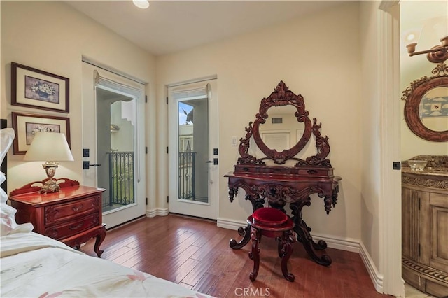 bedroom featuring baseboards, wood finished floors, and access to exterior