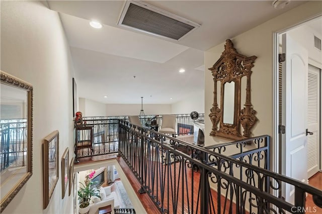 hall with wood finished floors, an upstairs landing, visible vents, and recessed lighting