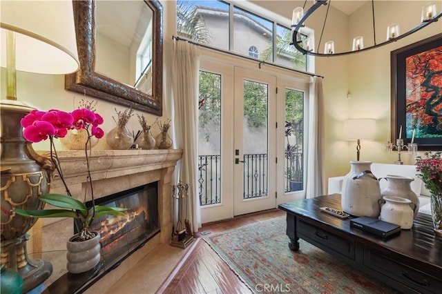 doorway to outside with wood finished floors, french doors, a glass covered fireplace, and a notable chandelier