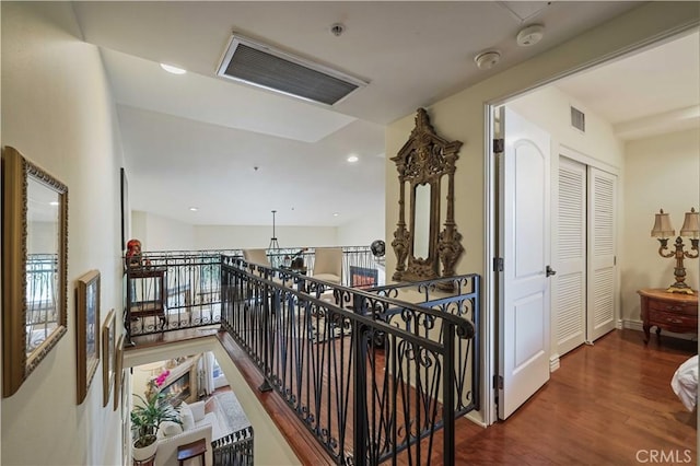 hallway featuring recessed lighting, visible vents, wood finished floors, and an upstairs landing