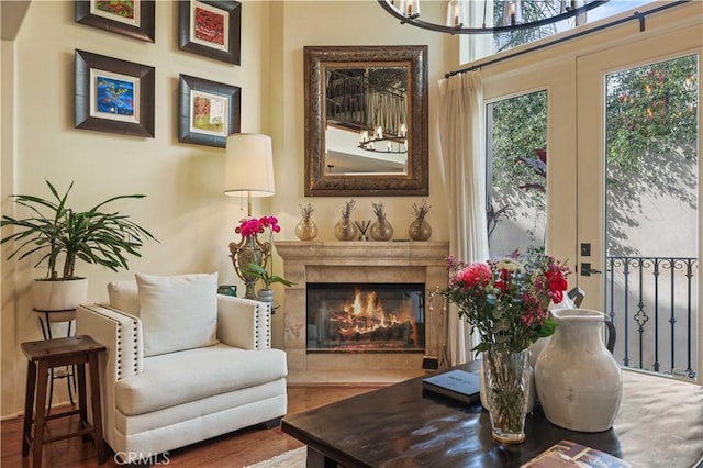 sitting room with french doors, a premium fireplace, and wood finished floors