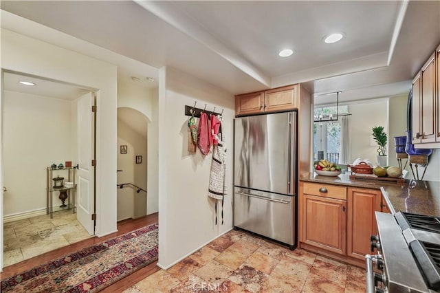 kitchen with stone tile floors, appliances with stainless steel finishes, arched walkways, and recessed lighting