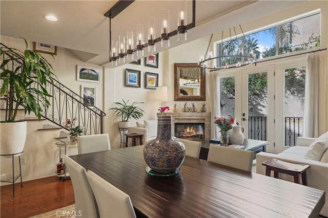 dining room featuring a notable chandelier, wood finished floors, a high end fireplace, french doors, and stairway