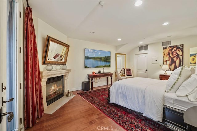 bedroom featuring a fireplace with flush hearth, visible vents, wood finished floors, and recessed lighting