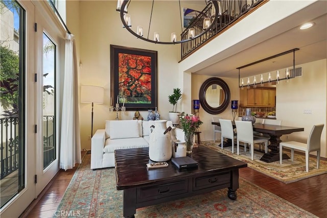 living area with visible vents, a high ceiling, and wood finished floors