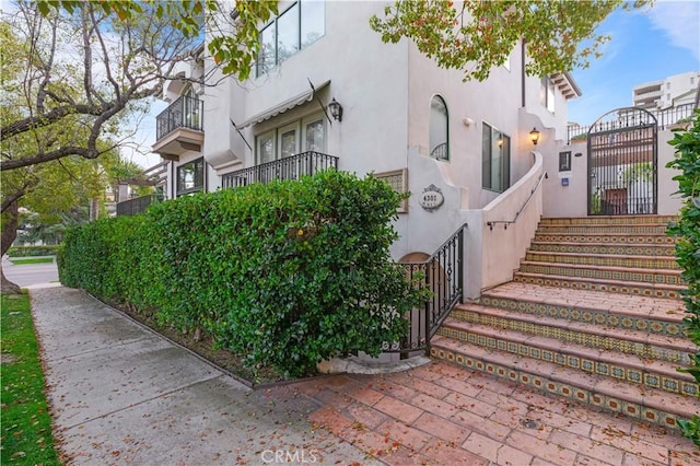 view of side of home featuring a gate and stucco siding