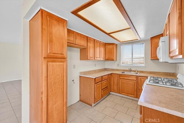 kitchen with a sink, white appliances, light tile patterned flooring, brown cabinetry, and light countertops