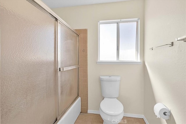 bathroom with tile patterned flooring, toilet, baseboards, and combined bath / shower with glass door