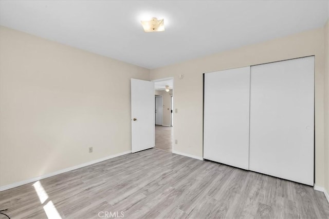 unfurnished bedroom with a closet, baseboards, and wood finished floors