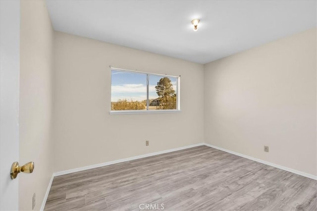 spare room featuring baseboards and wood finished floors