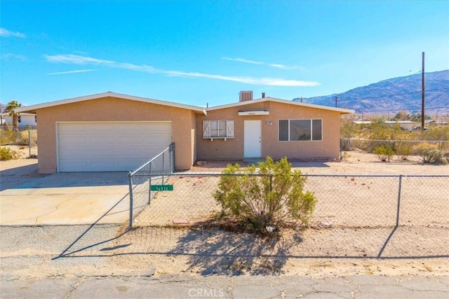 single story home featuring stucco siding, a fenced front yard, a mountain view, concrete driveway, and a garage