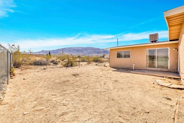 view of yard featuring central AC unit, a mountain view, and fence