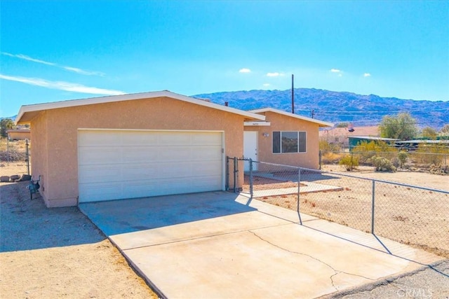 ranch-style home with concrete driveway, fence, a mountain view, and stucco siding