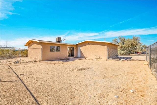 back of property with stucco siding, cooling unit, and fence