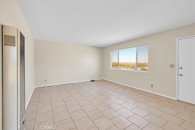 empty room featuring baseboards and a heating unit