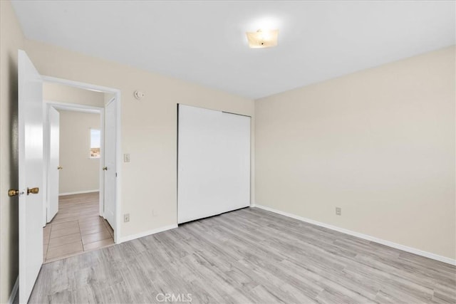 unfurnished bedroom featuring a closet, baseboards, and wood finished floors